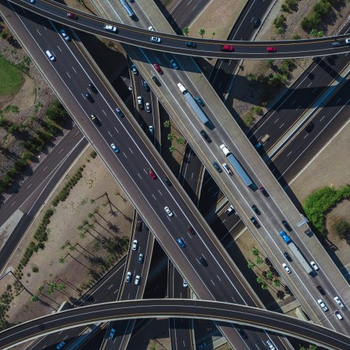 An overhead drone shot of a busy highway intersection full of traffic during daytime